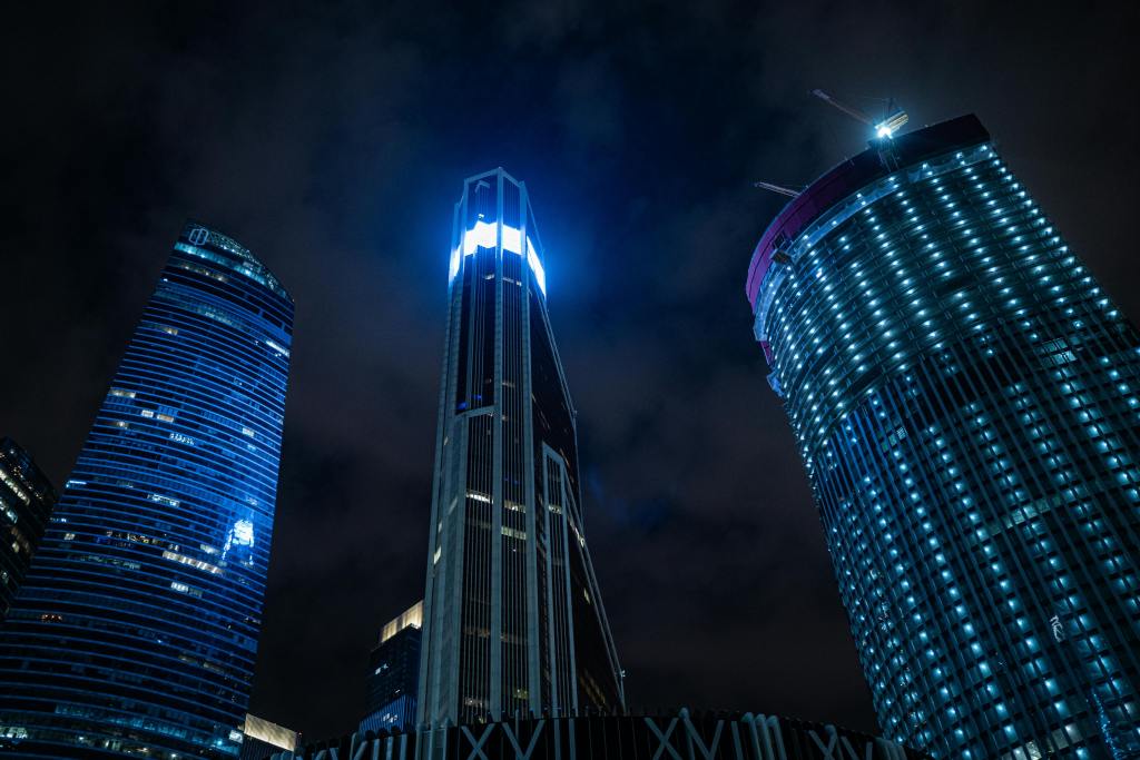 Night view of modern skyscrapers with illuminated facades against a dark sky.